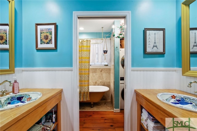 full bathroom featuring a shower with shower curtain, stacked washer and dryer, and wainscoting