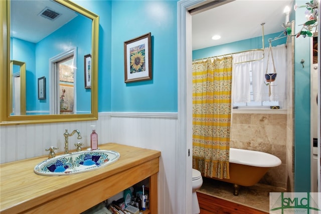 full bathroom featuring a wainscoted wall, visible vents, toilet, curtained shower, and a freestanding bath