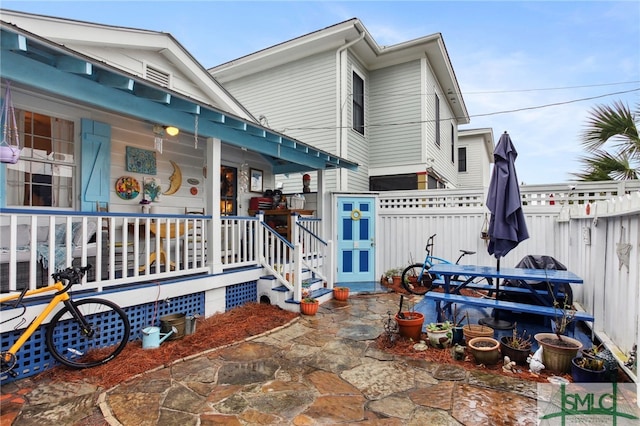 back of property featuring a porch and fence