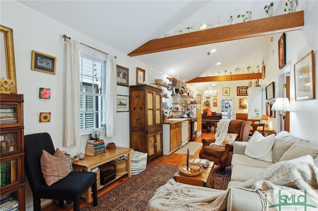 living area featuring vaulted ceiling, a notable chandelier, and light wood-type flooring