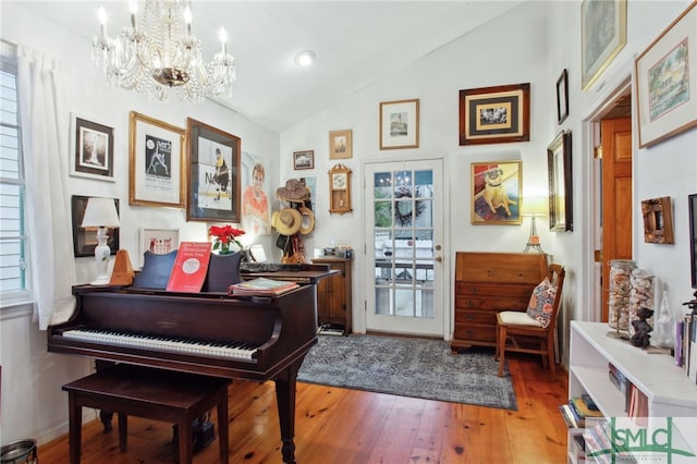 sitting room with a chandelier, a healthy amount of sunlight, light wood finished floors, and vaulted ceiling