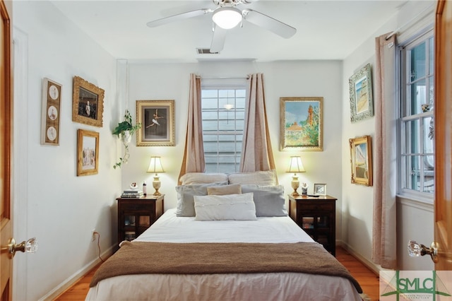 bedroom with ceiling fan, visible vents, baseboards, and light wood-style flooring