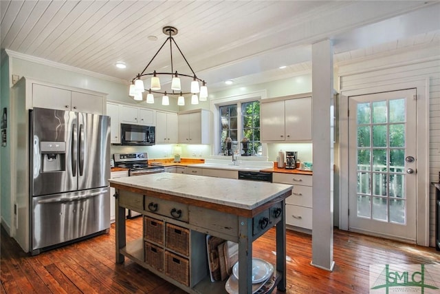 kitchen featuring crown molding, appliances with stainless steel finishes, hanging light fixtures, and white cabinets