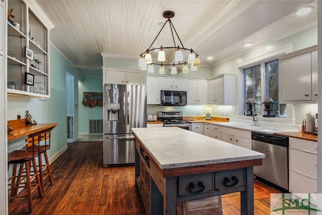 kitchen featuring decorative light fixtures, white cabinetry, ornamental molding, a center island, and stainless steel appliances