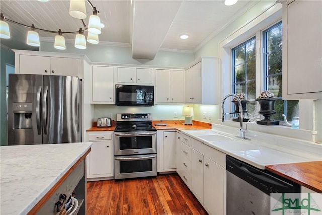 kitchen featuring pendant lighting, stainless steel appliances, sink, and white cabinets