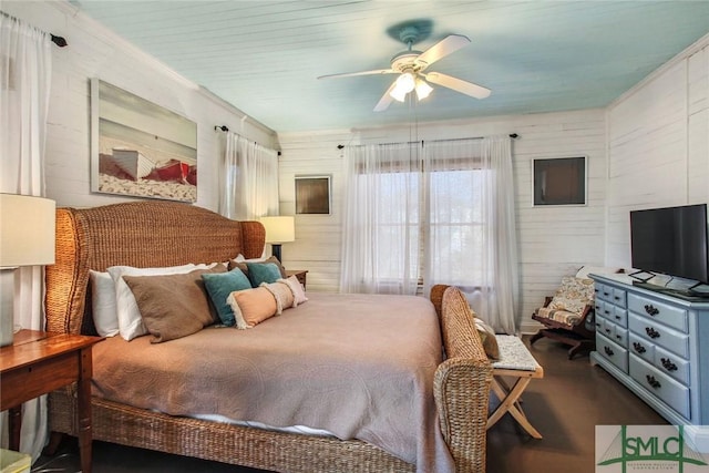 bedroom featuring ceiling fan and wood walls