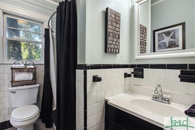 bathroom featuring vanity, tile walls, and toilet