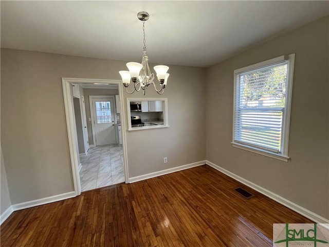 unfurnished dining area featuring an inviting chandelier and hardwood / wood-style flooring