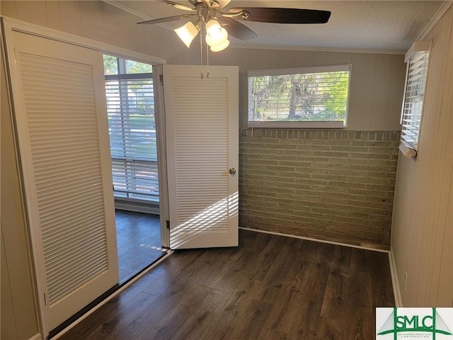 empty room featuring dark hardwood / wood-style flooring, ornamental molding, a healthy amount of sunlight, and brick wall