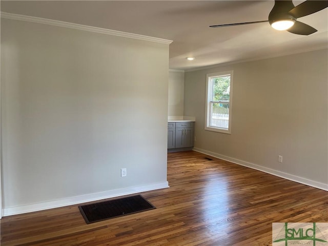 spare room featuring crown molding, dark wood-type flooring, and ceiling fan