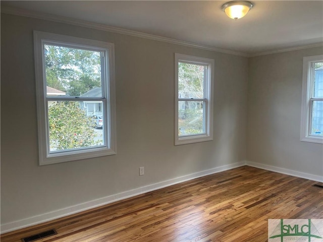 spare room featuring hardwood / wood-style floors, crown molding, and plenty of natural light