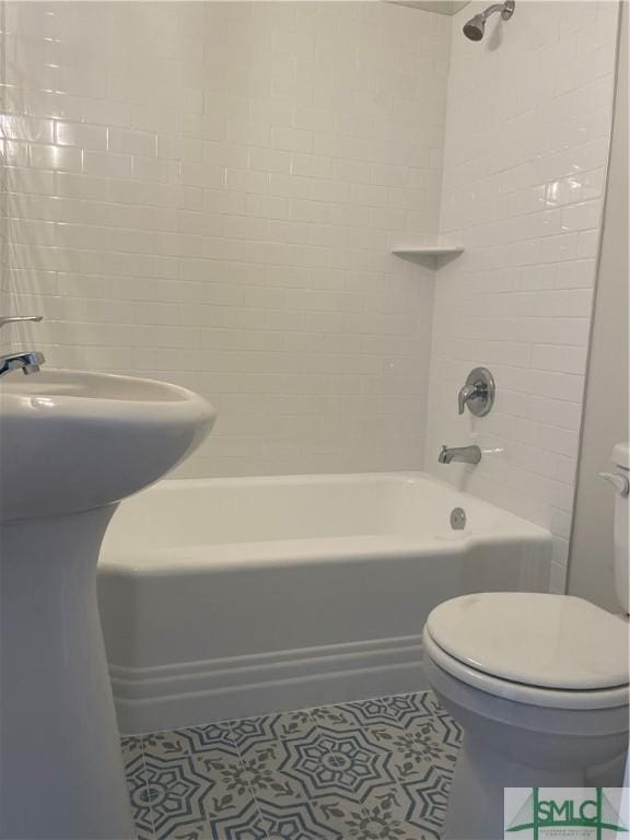 bathroom featuring tile patterned floors, toilet, and tiled shower / bath combo