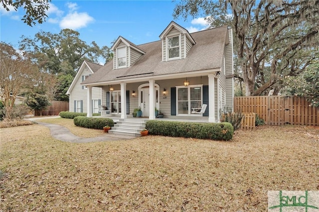 cape cod-style house featuring covered porch and a front lawn