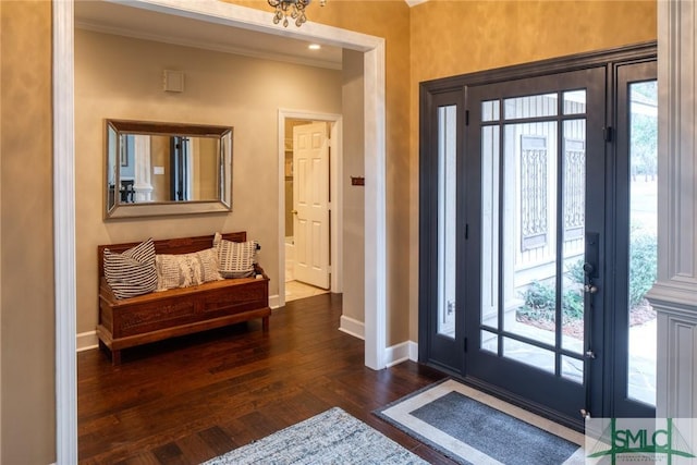 foyer entrance featuring dark hardwood / wood-style flooring, crown molding, and an inviting chandelier