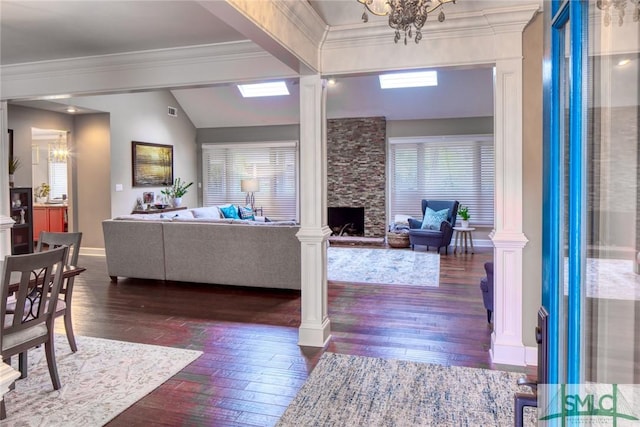 living room featuring crown molding, a fireplace, decorative columns, and vaulted ceiling