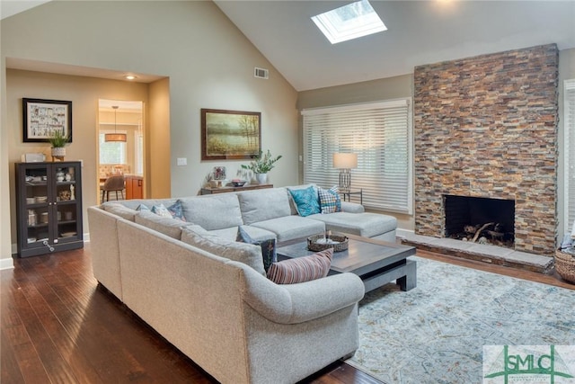 living room with high vaulted ceiling, dark wood-type flooring, a fireplace, and a skylight