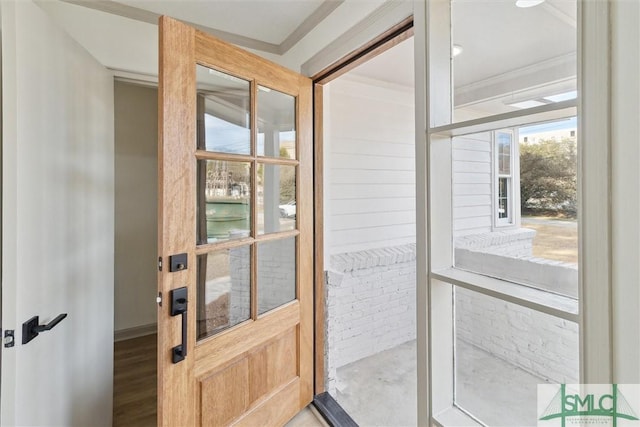 doorway featuring crown molding and brick wall