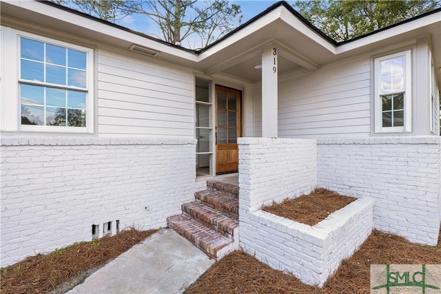 doorway to property with crawl space and brick siding