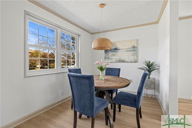 dining space featuring baseboards, ornamental molding, and wood finished floors