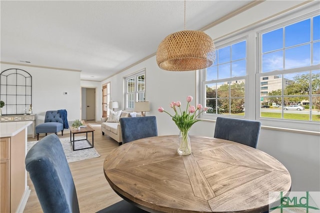 dining area with ornamental molding and light wood finished floors