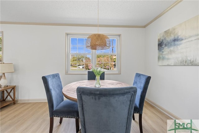 dining room with light wood-style flooring, a textured ceiling, baseboards, and crown molding