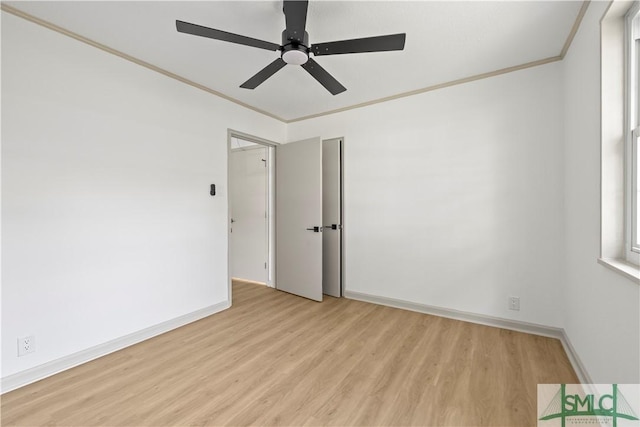 empty room with light wood-style floors, baseboards, and crown molding