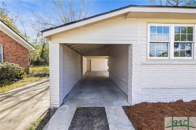 view of property exterior featuring an attached carport, concrete driveway, and brick siding