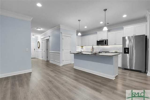 kitchen featuring a center island with sink, ornamental molding, appliances with stainless steel finishes, pendant lighting, and white cabinets