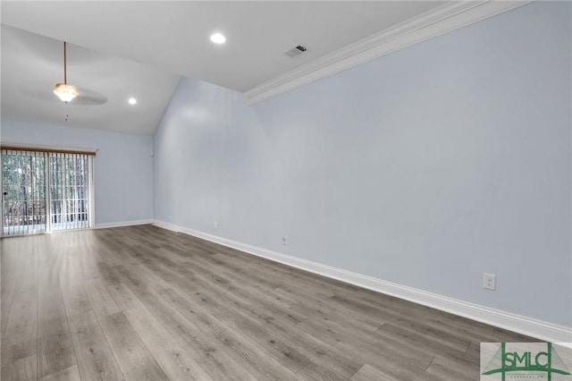 empty room featuring vaulted ceiling, ornamental molding, and light hardwood / wood-style floors