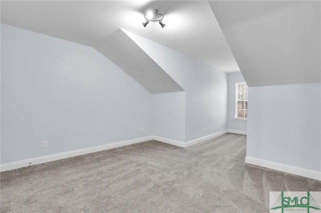 additional living space featuring light colored carpet and vaulted ceiling