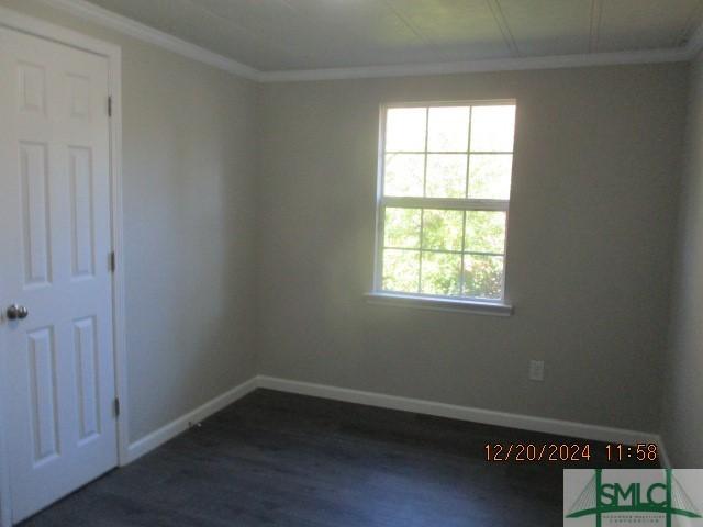 spare room featuring ornamental molding and dark wood-type flooring