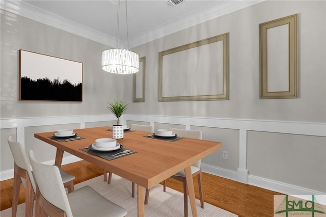 dining area featuring crown molding, an inviting chandelier, and light hardwood / wood-style floors