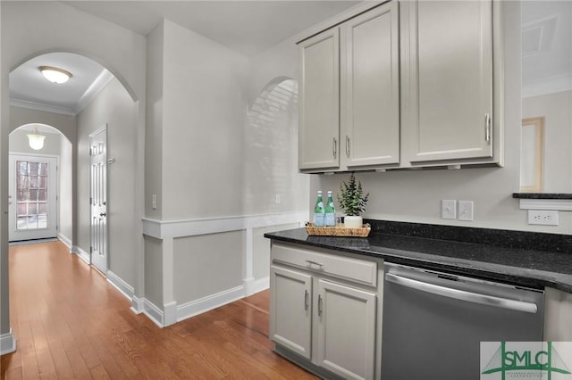 kitchen featuring dishwasher, crown molding, dark stone countertops, and light wood-type flooring