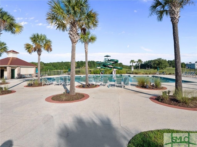 view of pool with a water slide and a patio