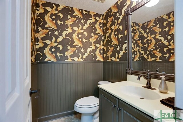 216 Olde Towne Rd, Savannah, GA 31410 - half bath featuring wallpapered walls, wainscoting, vanity, toilet, and a textured ceiling