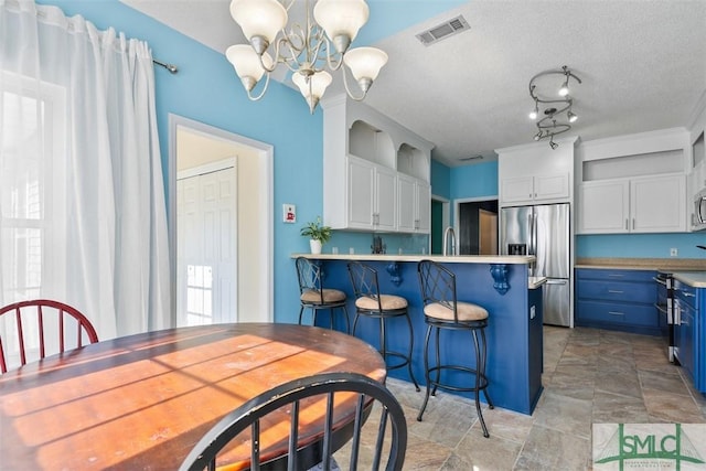 216 Olde Towne Rd, Savannah, GA 31410 - kitchen featuring stainless steel appliances, blue cabinetry, white cabinets, a chandelier, and a peninsula
