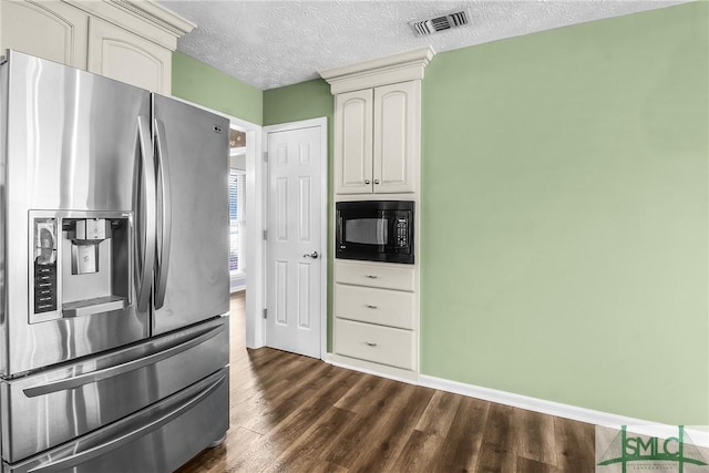 kitchen featuring black microwave, stainless steel fridge with ice dispenser, cream cabinets, dark wood-type flooring, and a textured ceiling