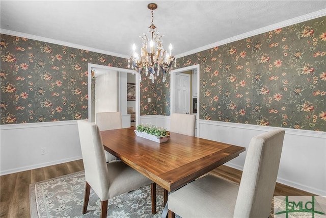 dining area featuring crown molding, wood-type flooring, and a notable chandelier