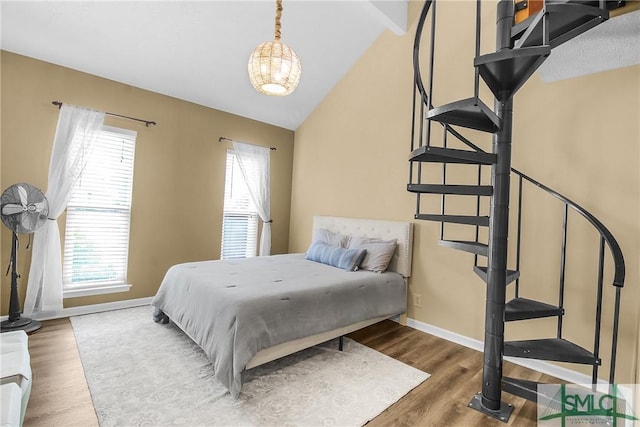 bedroom with multiple windows, hardwood / wood-style floors, and lofted ceiling