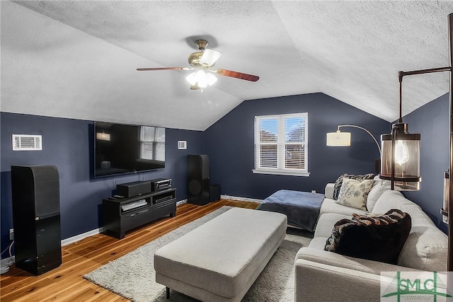 living room with hardwood / wood-style flooring, ceiling fan, lofted ceiling, and a textured ceiling