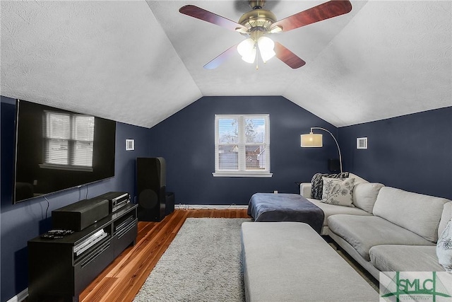 living room with ceiling fan, lofted ceiling, dark wood-type flooring, and a textured ceiling