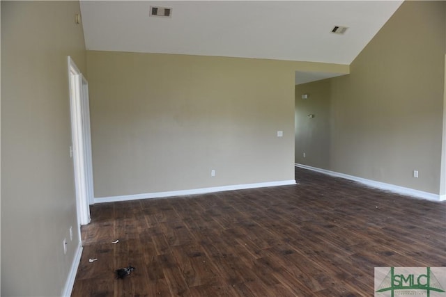 spare room with lofted ceiling and dark wood-type flooring