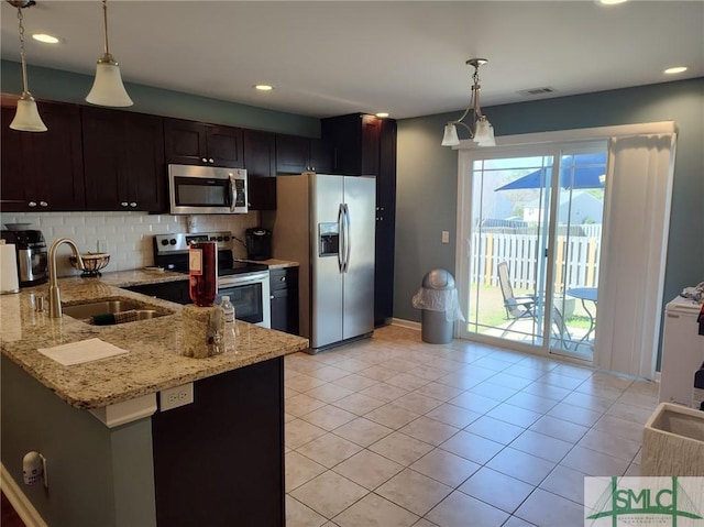 kitchen with appliances with stainless steel finishes, decorative light fixtures, sink, light stone counters, and kitchen peninsula