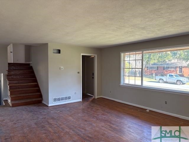 unfurnished living room with plenty of natural light, hardwood / wood-style floors, and a textured ceiling