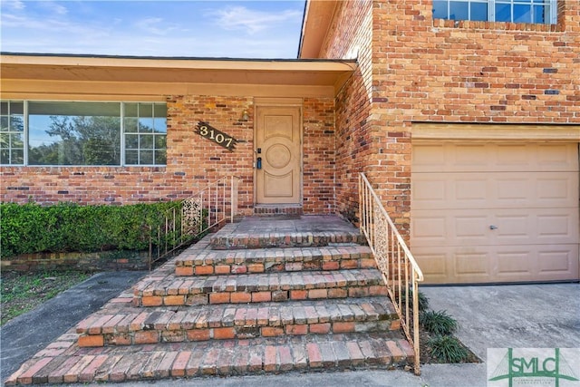 entrance to property with a garage and brick siding