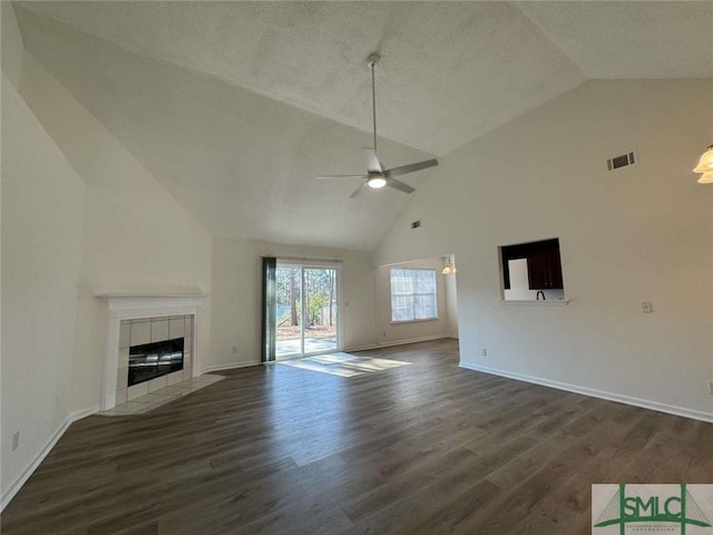 unfurnished living room with ceiling fan, high vaulted ceiling, dark wood-type flooring, and a fireplace