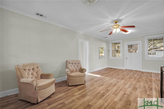 living area with light hardwood / wood-style floors, ceiling fan, and ornamental molding