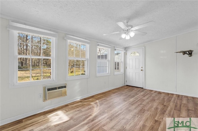 unfurnished sunroom with a wall mounted air conditioner, heating unit, and ceiling fan