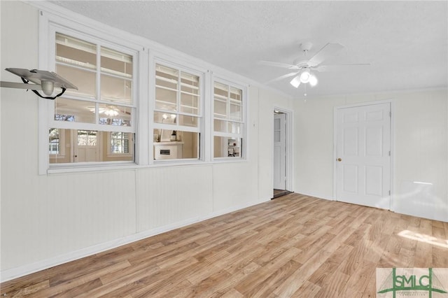 unfurnished room with ceiling fan, light wood-type flooring, and a textured ceiling