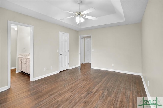 209 Mariners Way, Savannah, GA 31419 - unfurnished bedroom featuring dark wood-style flooring, baseboards, a raised ceiling, ensuite bath, and ceiling fan